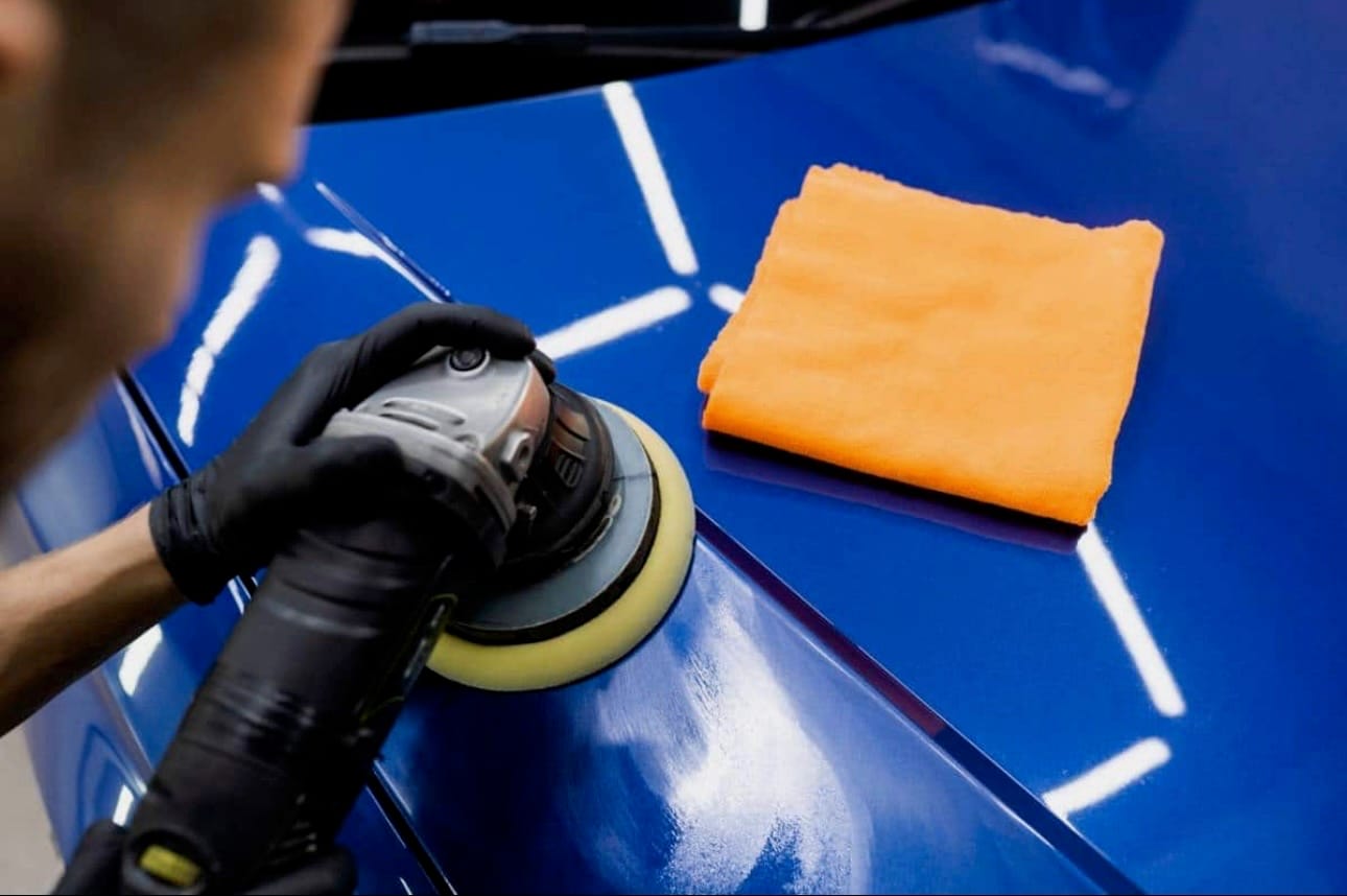 une personne qui fais un polissage de voiture avec des produits haut de gamme, il utilise une polisseuse avec un pad de grain moyen